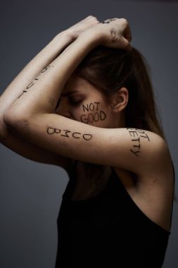 Vücut hüsranı üzerine yazıları olan bir kadın duygularını vurgulayarak yaşam tarzını gri arka planda tutuyor.