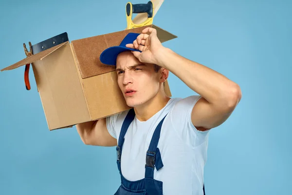 Εργαζόμενος άνθρωπος σε ενιαίο κουτί με εργαλεία φορτωτής παράδοση μπλε φόντο — Φωτογραφία Αρχείου