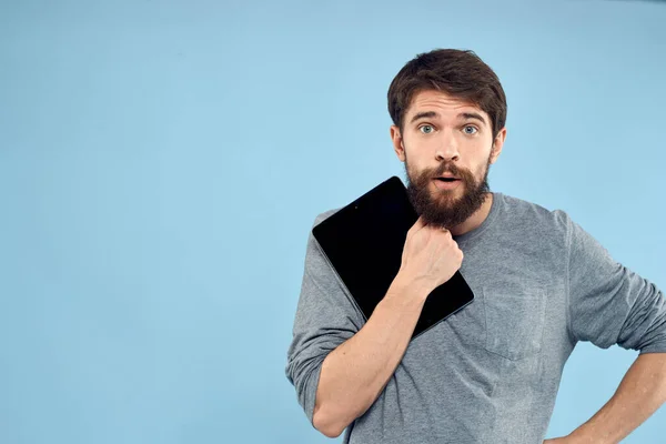 Hombre emocional con una tableta en las manos de un dispositivo inalámbrico tecnología de Internet estilo de vida fondo azul — Foto de Stock