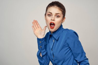 Açık arkaplanda kırmızı dudaklı ve mavi gömlekli güzel bir kadının portresi.