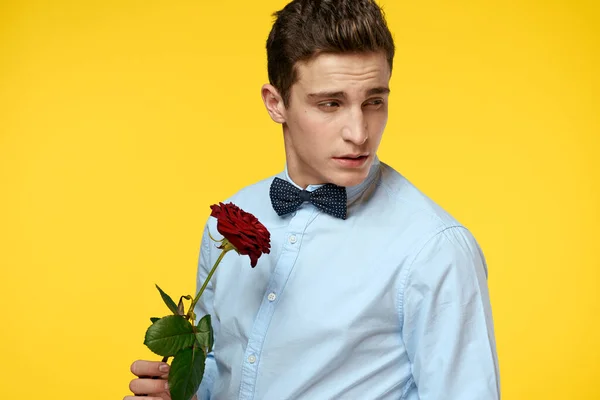 Portret van een man met een rode roos op een gele achtergrond en een lichte hemd strik gentleman — Stockfoto