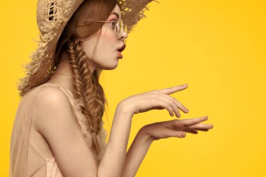 Saçları örgülü ve sarı arka planda şapkası olan güzel bir kadının portresi.