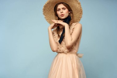 Mavi arka planda pembe elbiseli bir kız elleriyle romantik modeller yapıyor.