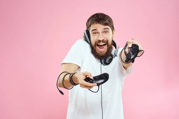 Ο άνθρωπος με joysticks στα χέρια ακουστικά διασκέδαση συναισθήματα παιχνίδι ροζ φόντο — Φωτογραφία Αρχείου
