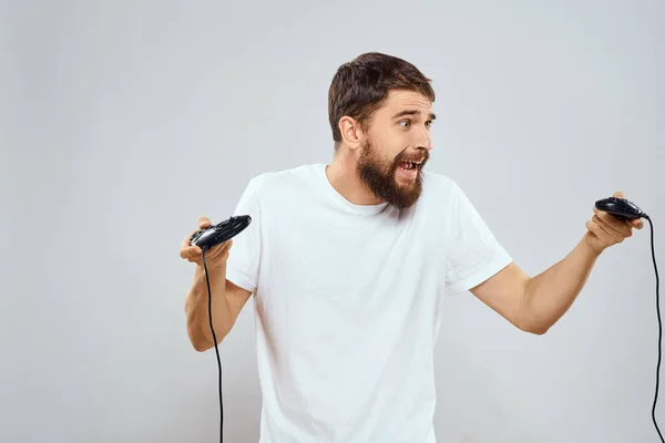 Un hombre tiene en sus manos dos joysticks jugando tecnología de ocio estilo de vida camiseta blanca —  Fotos de Stock