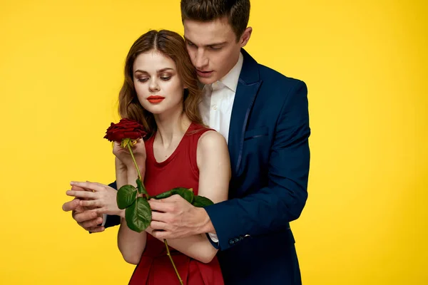 Los amantes de los hombres mujer con rosa roja en las manos vacaciones románticas fondo amarillo familiares amigos. — Foto de Stock