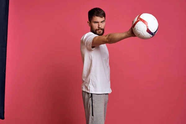 Uomo con un pallone da calcio su sfondo rosa energia gesticolare con le mani allenatore emozioni modello — Foto Stock