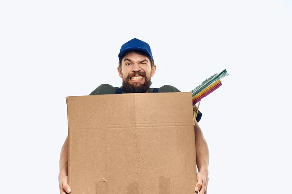 Ένας άνδρας με στολή εργασίας με ένα κουτί στα χέρια του να παραδίδει εργασίες μεταφοράς — Φωτογραφία Αρχείου
