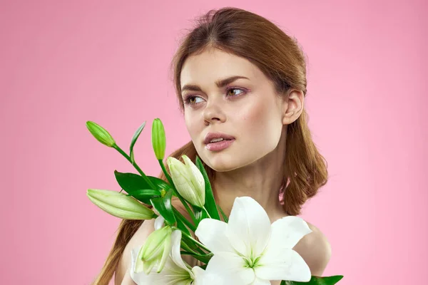 Mulher bonita segurando buquê de flores em mãos ombros nus fundo rosa charme — Fotografia de Stock