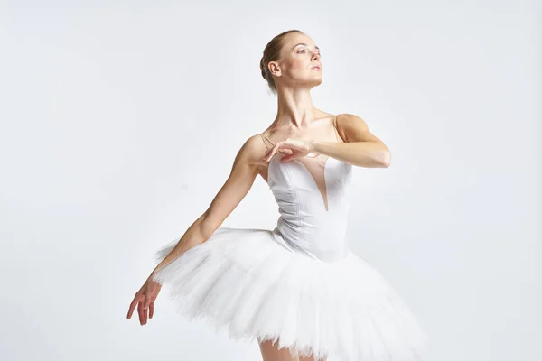 Bailarina em um tutu branco realizando dança exercício flexibilidade luz fundo — Fotografia de Stock