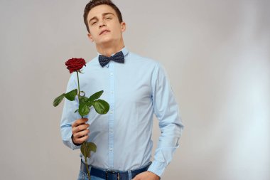 Kırmızı güllü ve açık renk gömlekli yakışıklı bir adamın portresi.