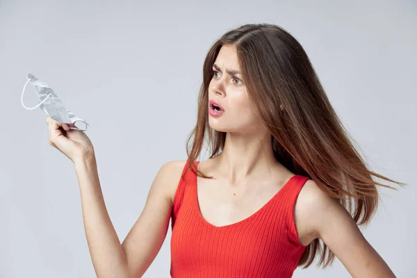 Mulher com uma máscara médica em suas mãos olha para o lado Red T-shirt emoções — Fotografia de Stock