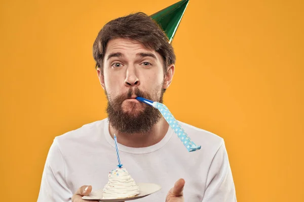 Un hombre barbudo con un pastel y con una gorra celebrando su cumpleaños — Foto de Stock