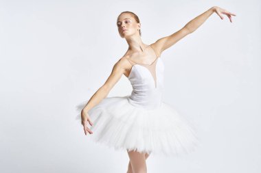 Beyaz etekli balerin dans egzersizi yapıyor. Esnek arka plan.