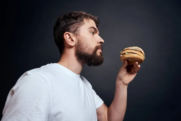 Muž jíst hamburger fast food restaurace Gourmet jíst tmavé pozadí — Stock fotografie