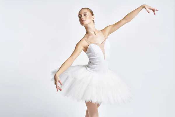 Bailarina em um tutu branco realizando dança exercício flexibilidade luz fundo — Fotografia de Stock