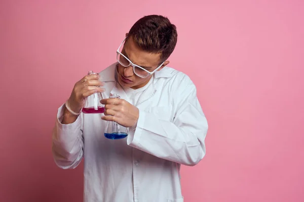 Assistant de laboratoire masculin avec des flacons dans les mains d'une substance chimique liquide multicolore — Photo