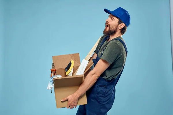 Trabalhador homem em caixa uniforme ferramentas construção azul fundo — Fotografia de Stock