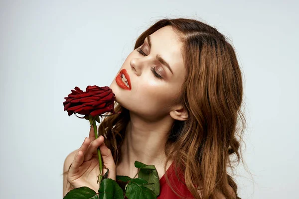 Bella donna in un abito rosso tiene una rosa in mano un regalo fiori decorazione aspetto attraente — Foto Stock