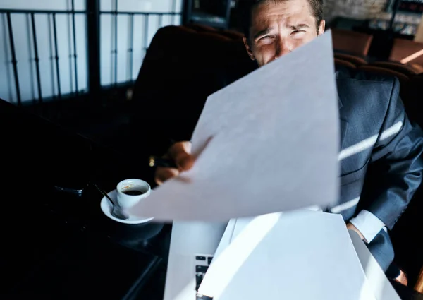 Homem de negócios em um terno de café na frente de emoções laptop tecnologia documentos oficiais — Fotografia de Stock