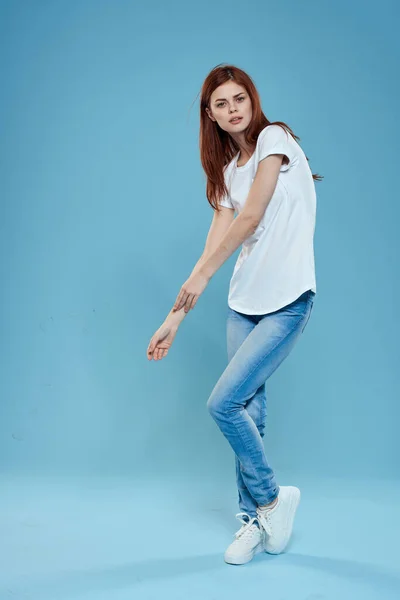 Beyaz tişörtlü, mavi kot pantolonlu, tam gelişmiş stüdyo mavi arka planlı güzel bir kadın. — Stok fotoğraf