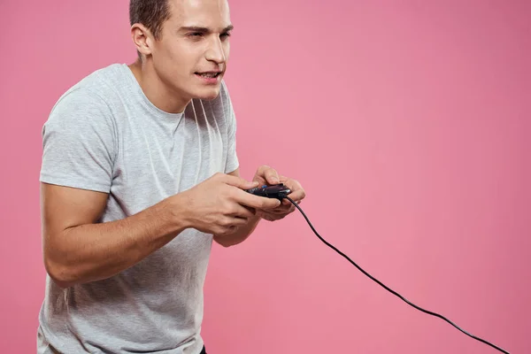 Hombre alegre con joystick alambre tecnología entretenimiento estilo de vida rosa fondo —  Fotos de Stock