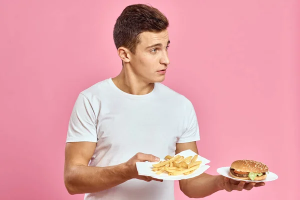 Mann mit Hamburger und Pommes Fast Food Kalorien rosa Hintergrund frische Lebensmittel Emotionen Modell — Stockfoto