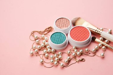 Göz falı aksesuarlar, boncuklar makyaj fırçaları pembe arka planda profesyonel kozmetik ürünleri koleksiyonu.