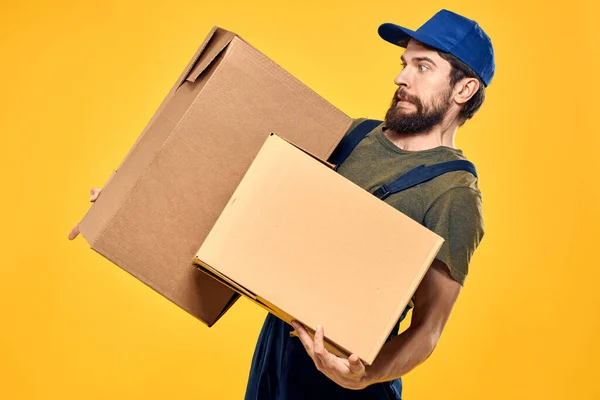 Muž v pracovním formuláři krabice s nakládacím nářadím žluté pozadí — Stock fotografie