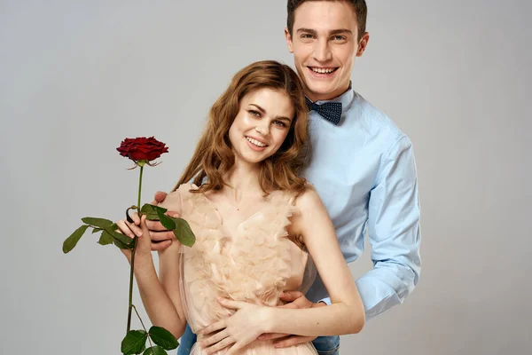 Mladý pár romantika objetí vztah datování červená růže světlo studio pozadí — Stock fotografie