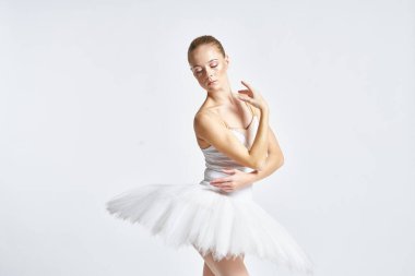 Beyaz etekli balerin dans egzersizi yapıyor. Esnek arka plan.