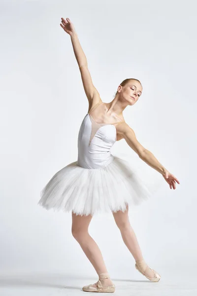 Balerina w białym tutu wykonując ćwiczenia taneczne elastyczność światło tło — Zdjęcie stockowe
