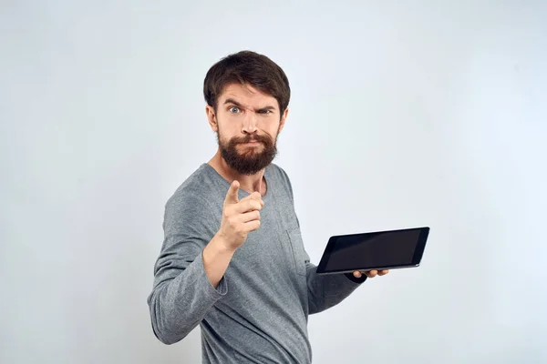 Ein bärtiger Mann mit einem Tablet in der Hand eine graue Jacke Technologie Internet-Licht Hintergrund — Stockfoto