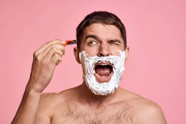 Man med rakhyvel och vitt skum på ansiktet rosa bakgrund naken bål bad behandlingar — Stockfoto