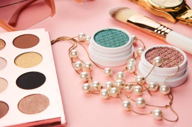 Göz falı aksesuarlar, boncuklar makyaj fırçaları pembe arka planda profesyonel kozmetik ürünleri koleksiyonu.