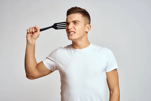 Guy s kuchyňským nářadím v rukou na lehkém pozadí oříznutý pohled na emoce zábavný model — Stock fotografie