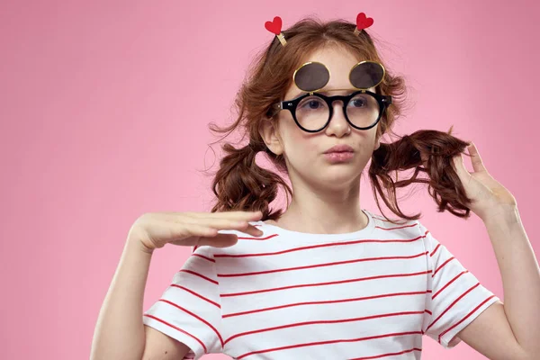 Menina alegre com tranças óculos de sol listrado t-shirt estilo de vida rosa fundo — Fotografia de Stock