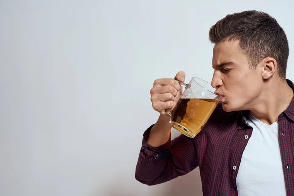 Fylld man med en mugg öl semester alkohol livsstil i en röd skjorta känslor ljus bakgrund — Stockfoto