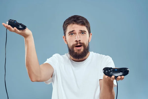 Hombre celebración gamepads juegos estilo de vida tecnología consola emociones blanco camiseta azul fondo —  Fotos de Stock