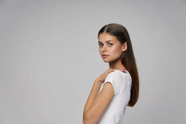 A woman in a white t-shirt holds her hands on her shoulders cropped view — Stock Photo, Image