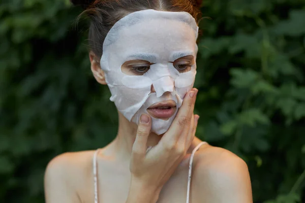 Mujer hermosa máscara anti-envejecimiento toque su cara con su mano en la naturaleza hombros desnudos — Foto de Stock