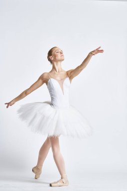 Beyaz etekli bir balerin hafif bir arka planda dans etti.