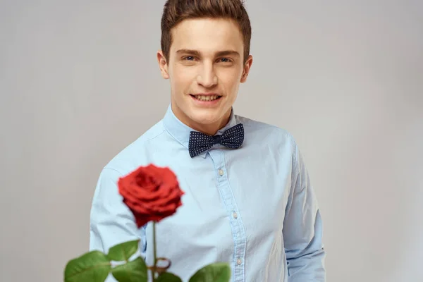 Retrato de un hombre guapo con una rosa roja y con una camisa ligera vista recortada — Foto de Stock