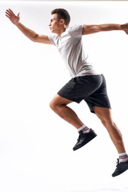 Spor şortlu bir sporcu ve arka planda bir tişört var ve tam gelişim göstererek kenarda koşuyor.