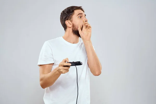Un hombre con un mando en sus manos jugando juegos ocio estilo de vida tecnología blanco camiseta fondo claro —  Fotos de Stock