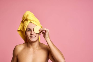 Kafasında havlu ve elinde sarı bir sünger olan bir adam. Kozmetik prosedürü. Yüzü temiz.