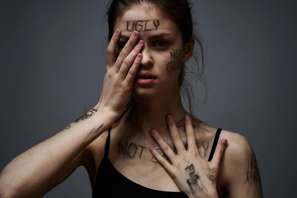 Mulher com inscrições ofensivas em seu corpo tocando-se com as mãos estresse frustração ódio — Fotografia de Stock
