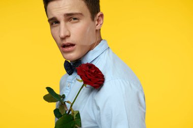 Gömlekli ve papyonlu bir beyefendi boynunda sarı arka planda kırmızı gül