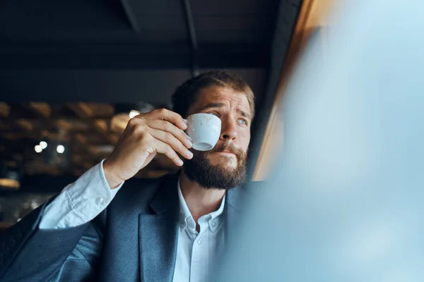 Homme d'affaires assis dans un café avec une tasse de café dans ses mains devant un ordinateur portable communication technologique — Photo