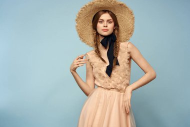 Mavi arka planda pembe elbiseli bir kız elleriyle romantik modeller yapıyor.
